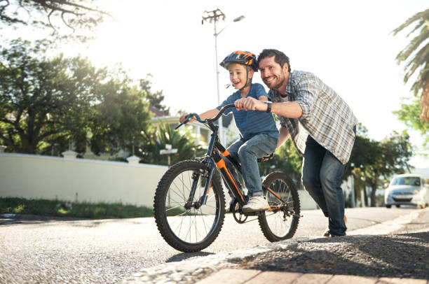 Shot of a young man teaching his son how to ride a bike